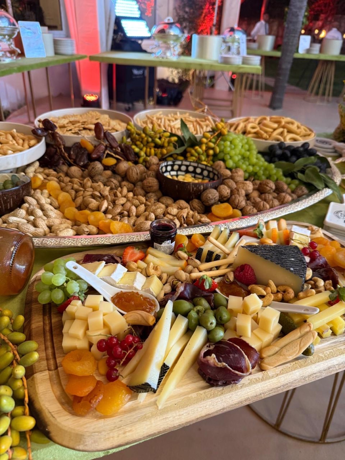Table de grazing : fromages à la coupe, raisin, fruits secs, noix et gressins sur planches de bois